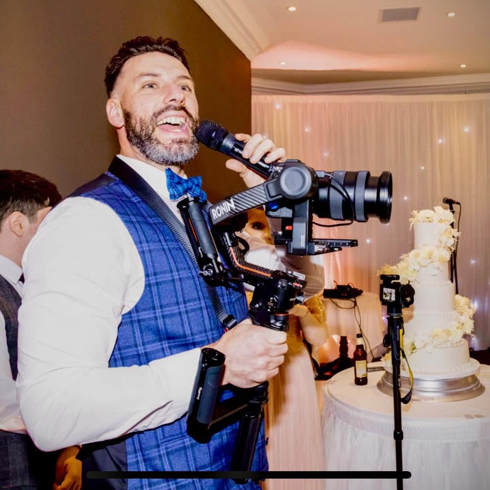 Andrew filming a wedding reception, holding a Ronin gimbal rig and a microphone.
