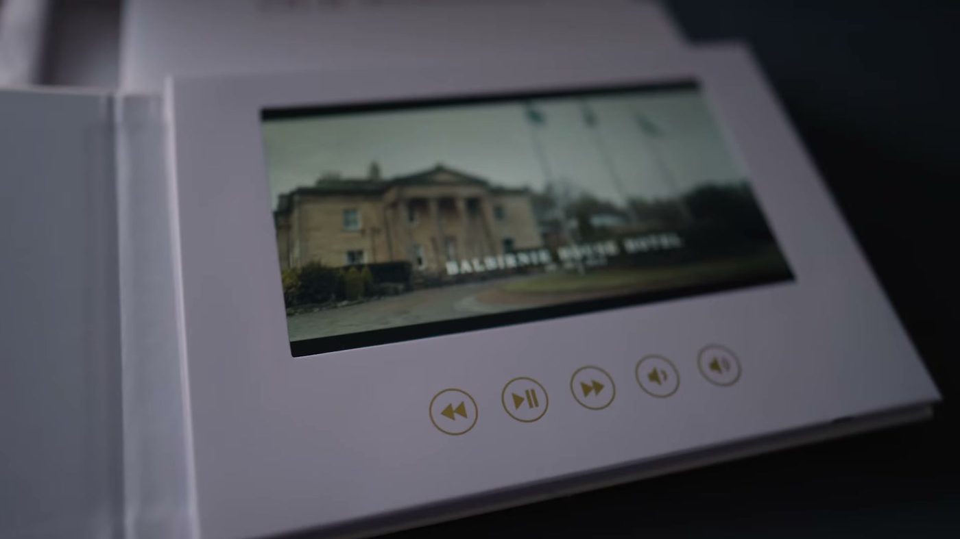 An open video memory book, a hardcover book with a screen set into the right-hand page, playing a wedding film at Balbirnie House Hotel.
